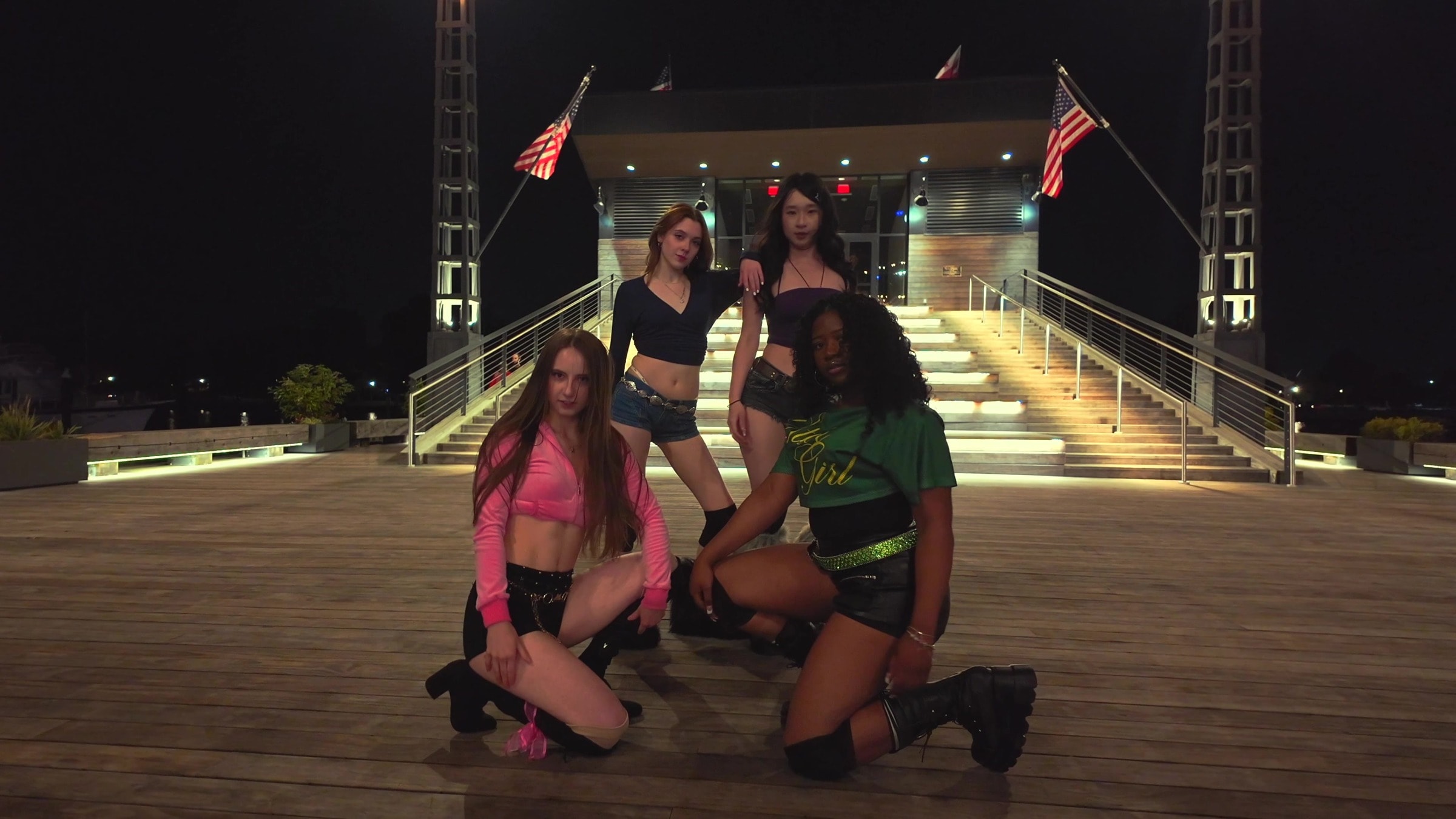 Four N2DC dancers holding the final Tweak formation in front of illuminated outdoor steps at night.
